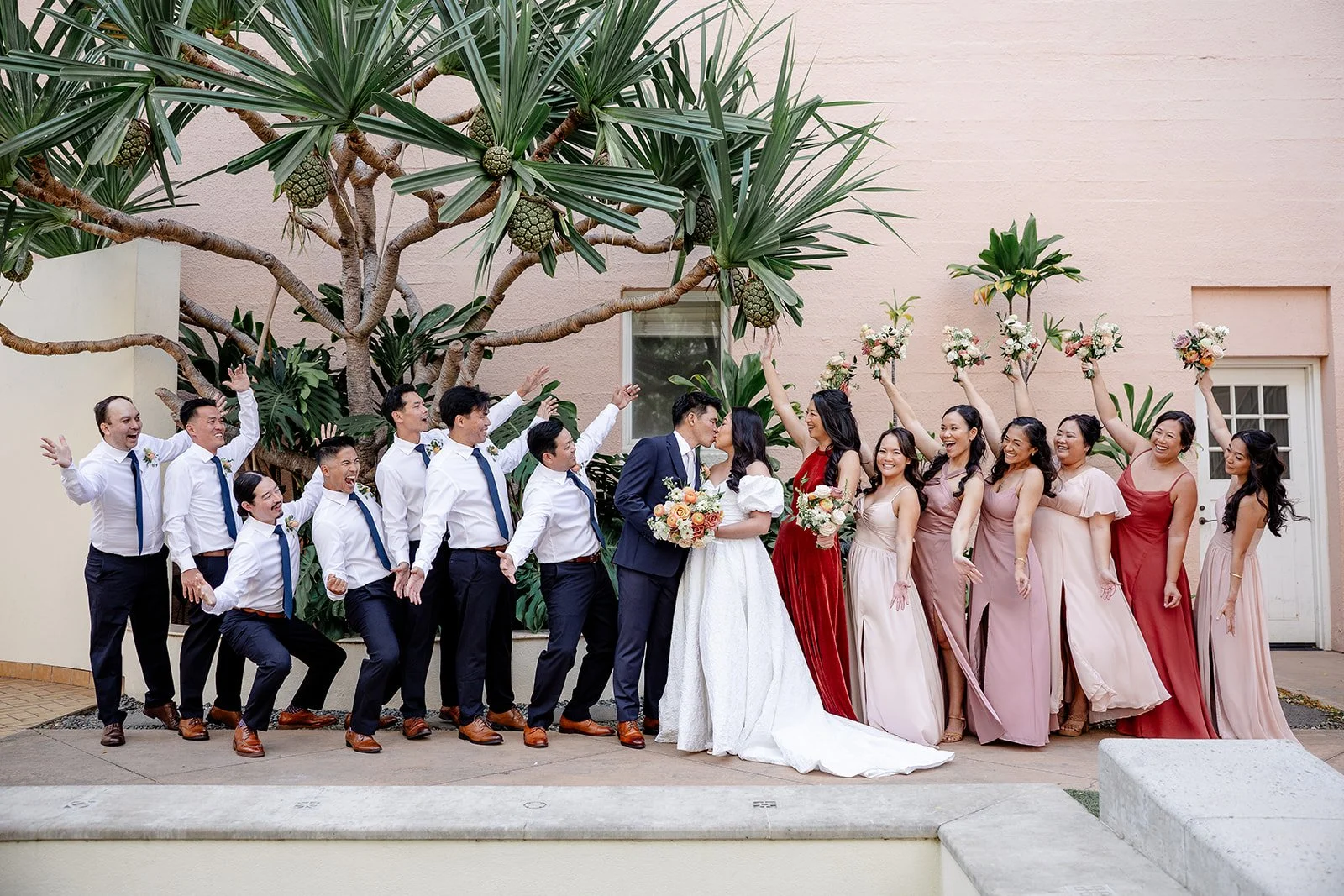 bride and groom with wedding party in mauve and red dresses and navy suits