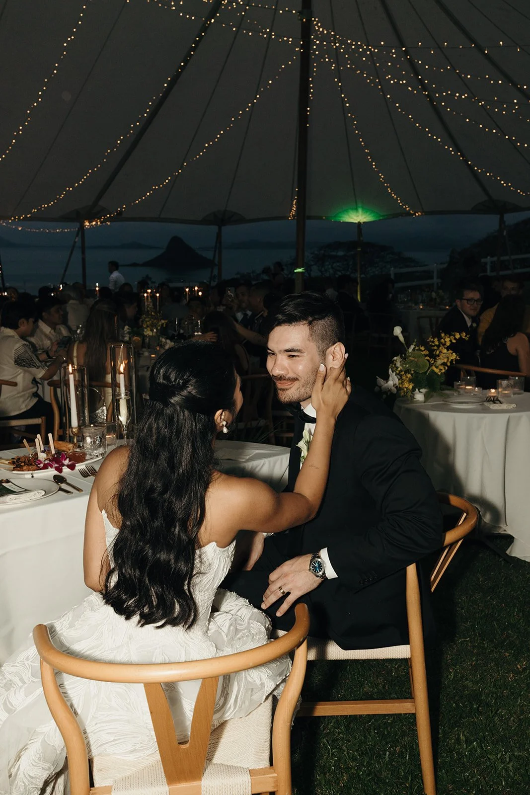 bride and groom under twinkle lights in reception tent in hawaii