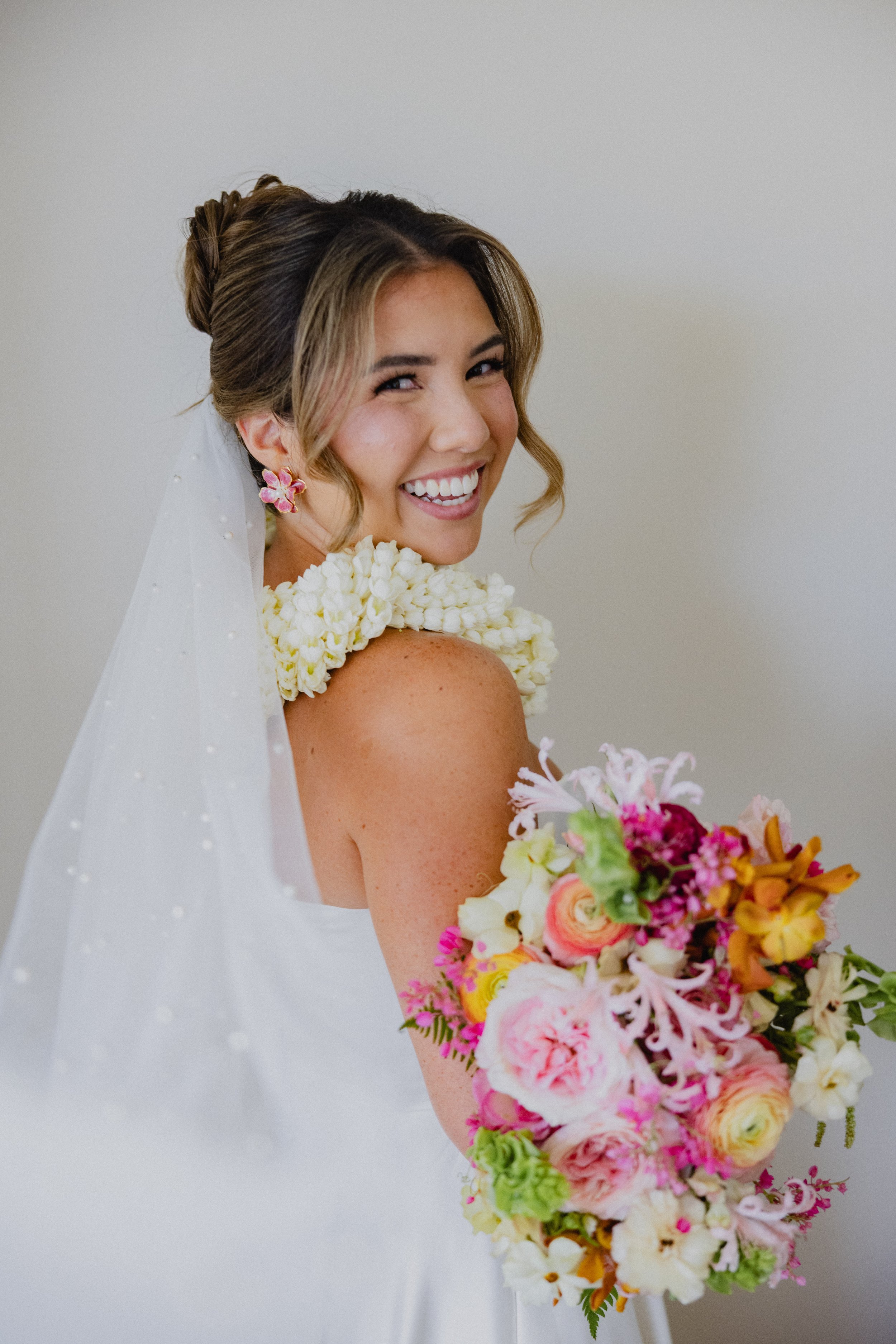 bride with lei and pink and orange bouquet