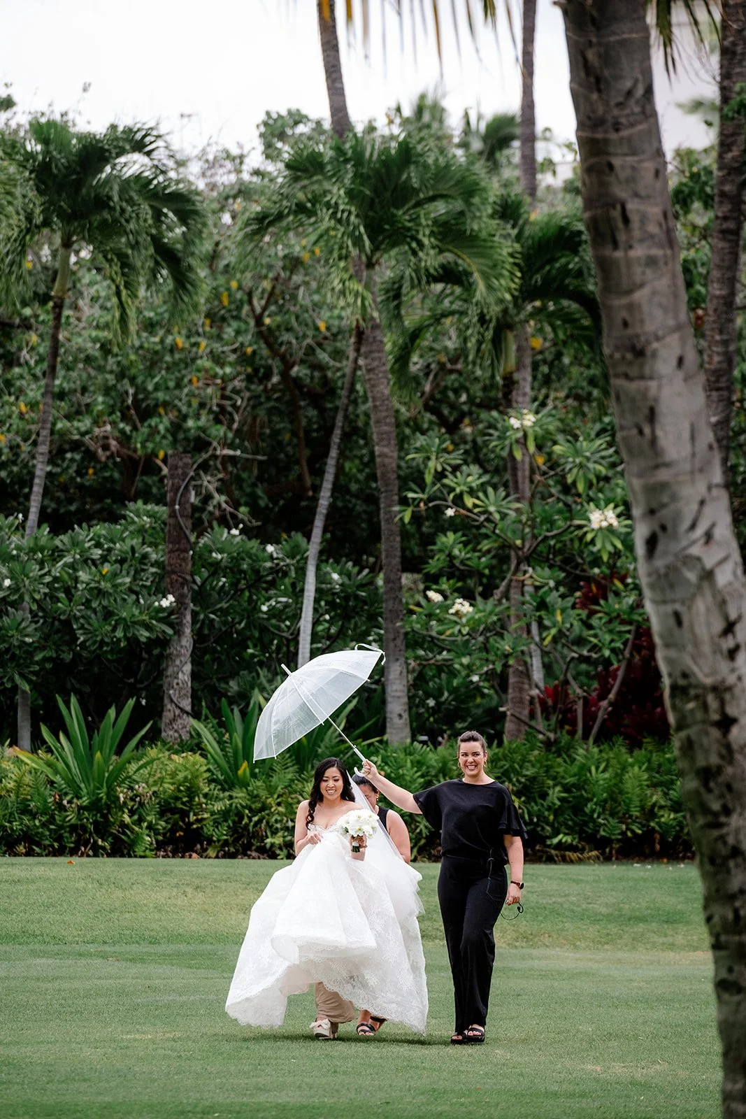 wedding planner holding umbrella over bride in hawaii