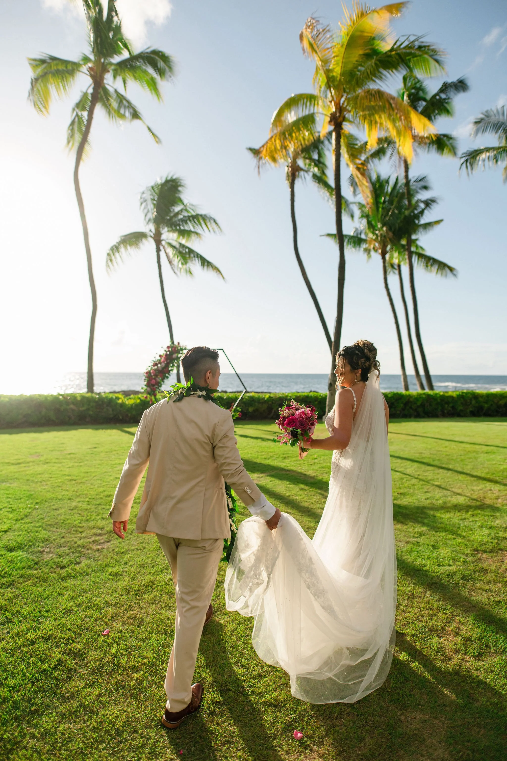 groom holding brides dress near beach in hawaii