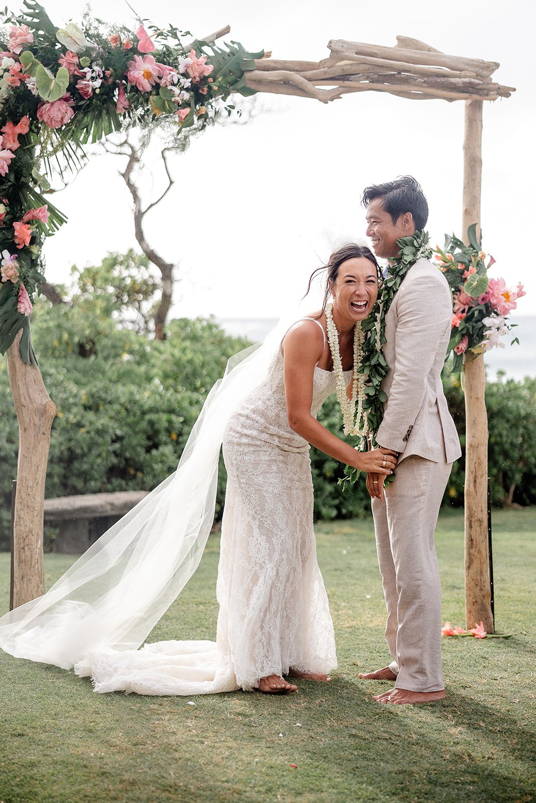 bride and groom in front of wedding arch in hawaii