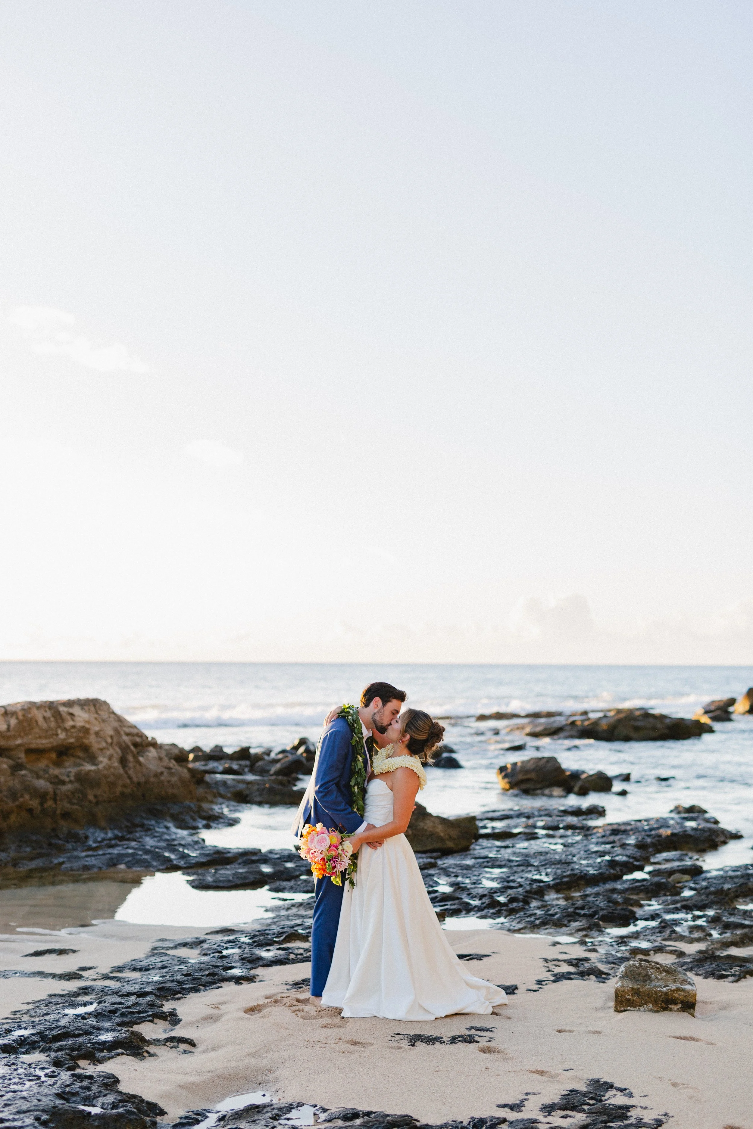 bride and groom kissing on beach in hawaii