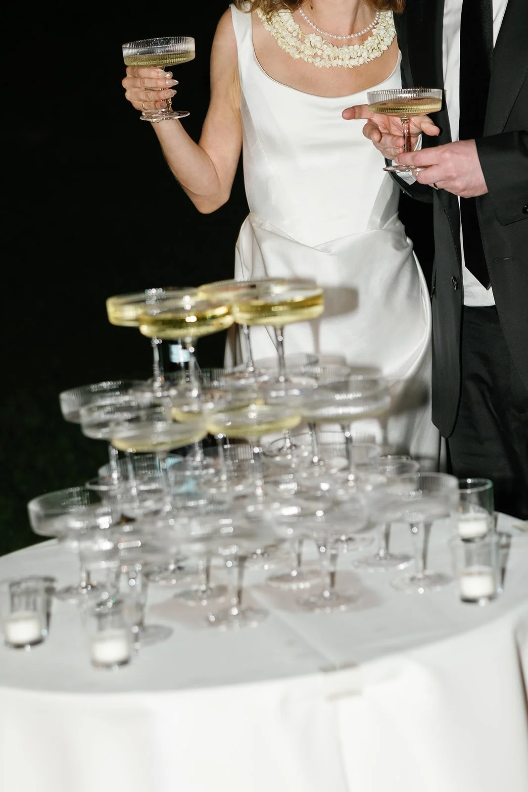 Bride and groom cheers after pouring their champagne tower, styled by Hawaii wedding planner Love Letter Weddings at Paliku Gardens