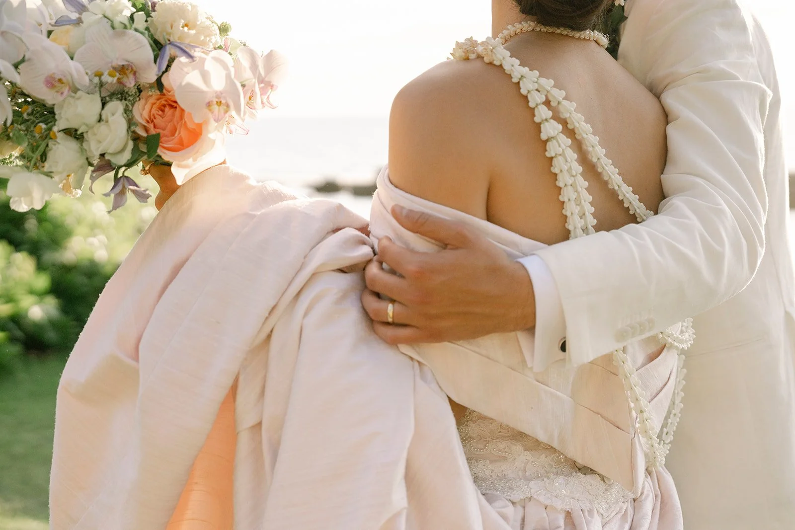 groom holding bride with lei on