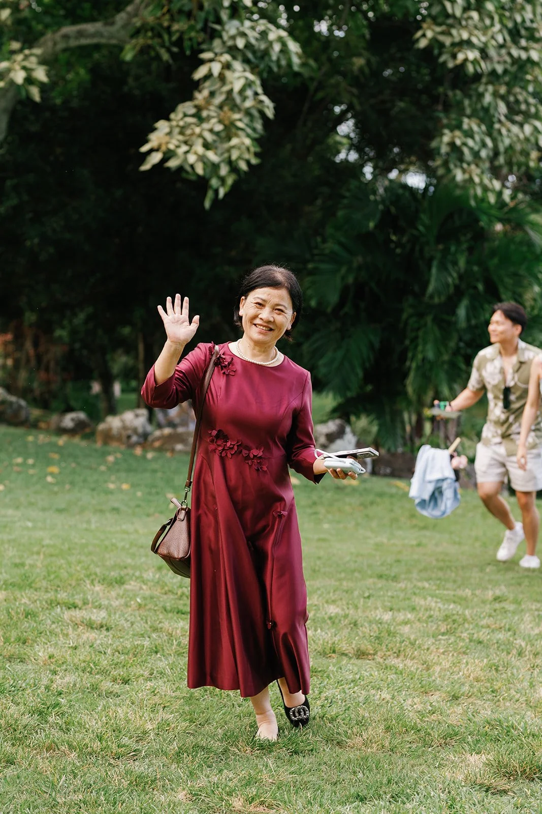 Groom's mom smiling and waving to camera heading towards ceremony