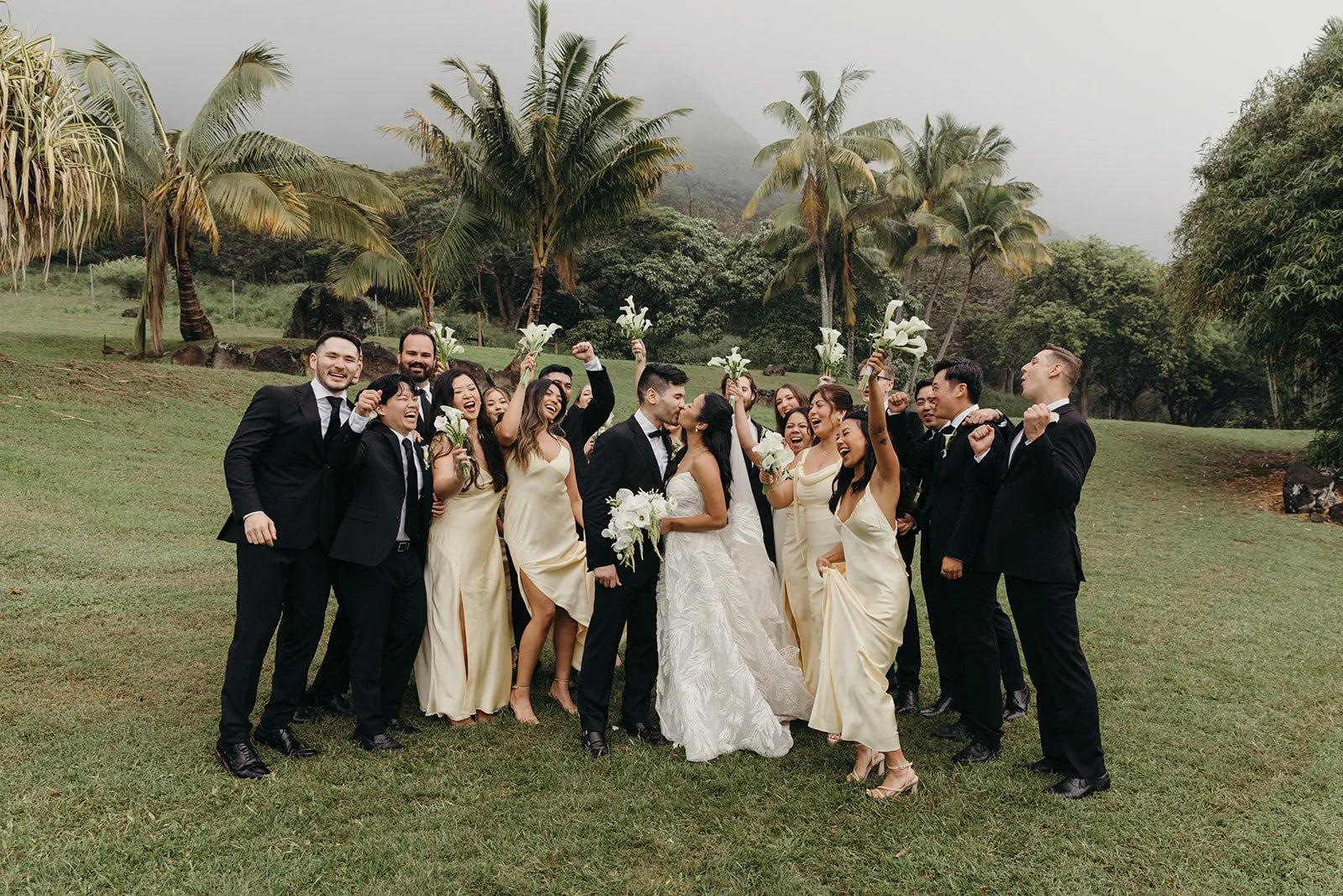 bride and groom with wedding party in front of palm trees in hawaii