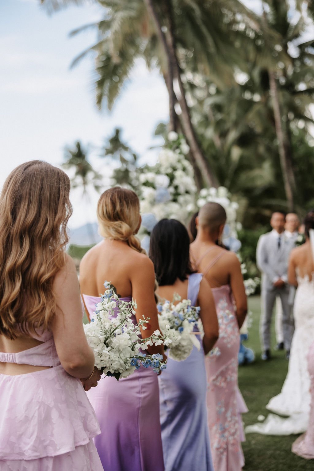 Bridesmaids in lavender bridesmaid dresses stand at the altar with bride during ceremony.