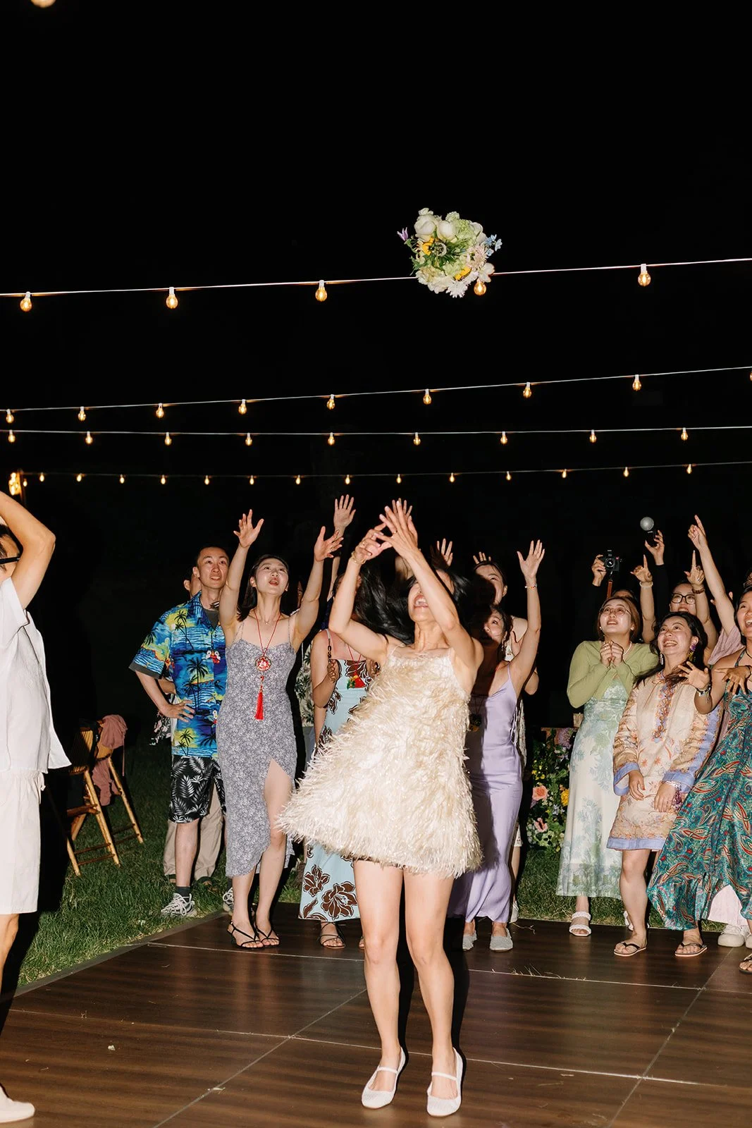 Bride tossing bouquet to the ladies behind her