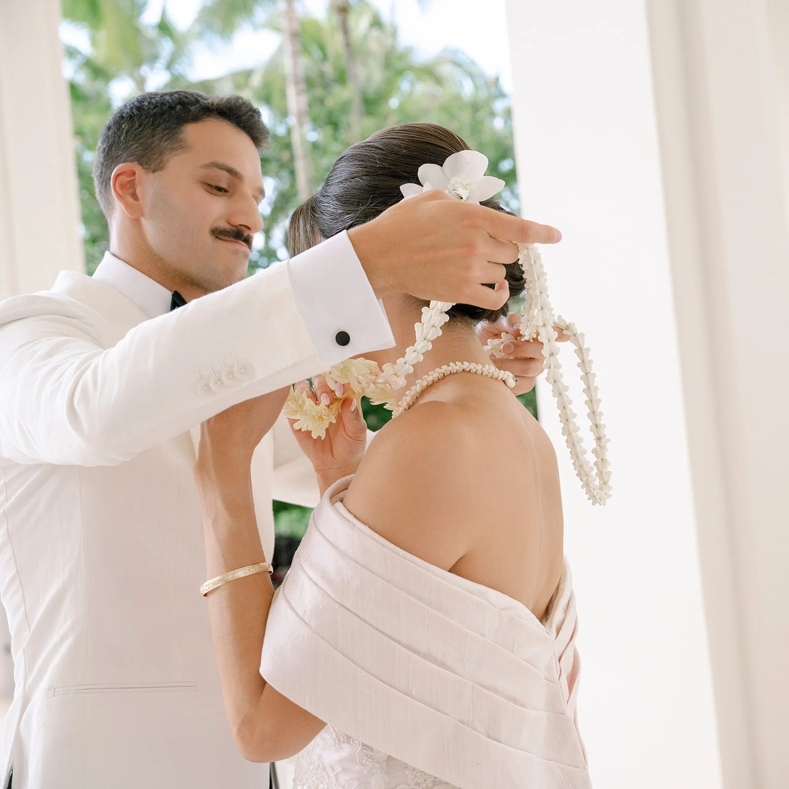 groom putting lei on bride