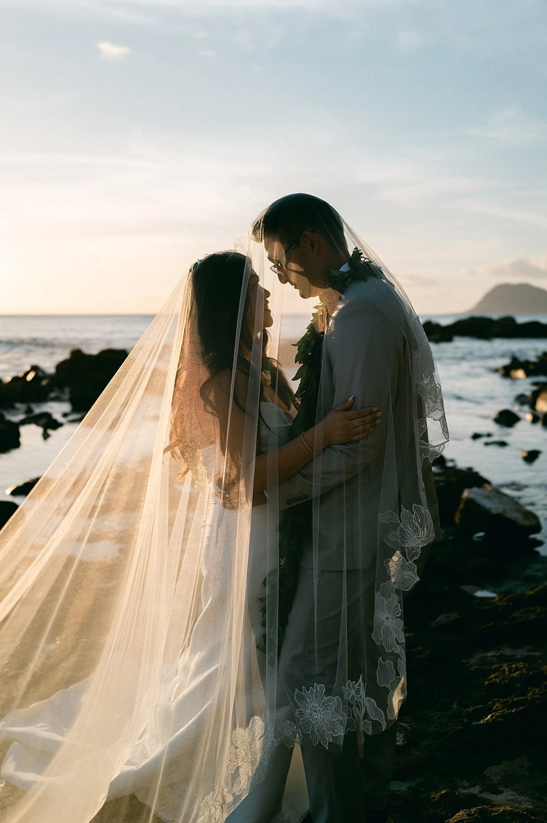 bride and groom under veil during sunset