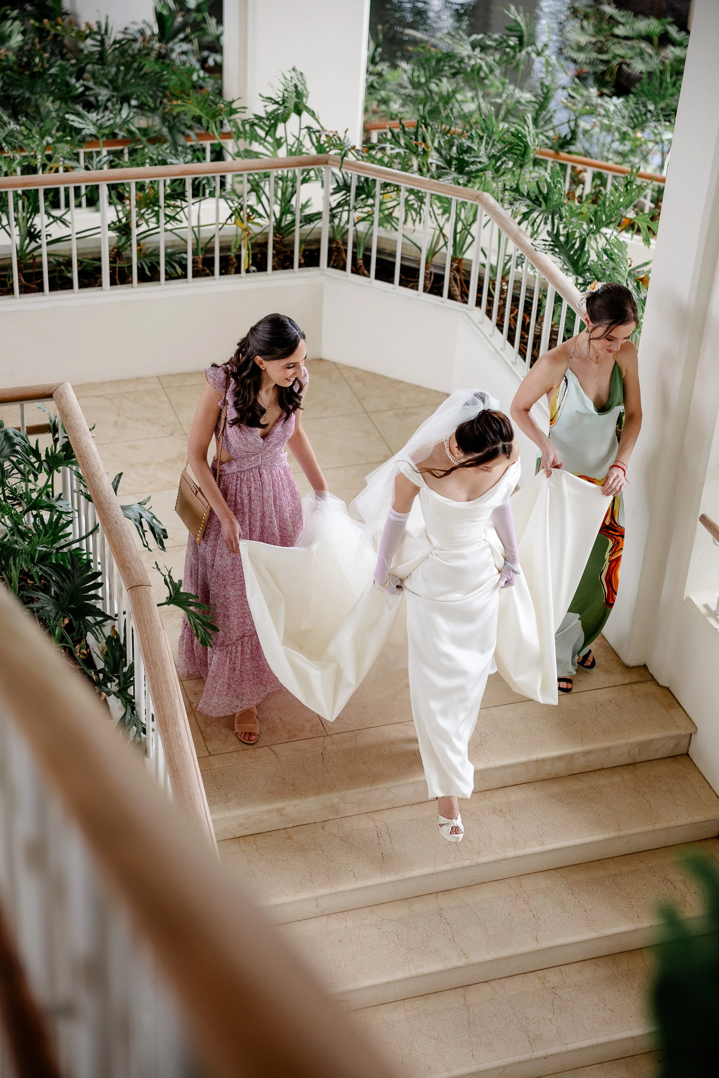 bridesmaids carrying brides train down stairs