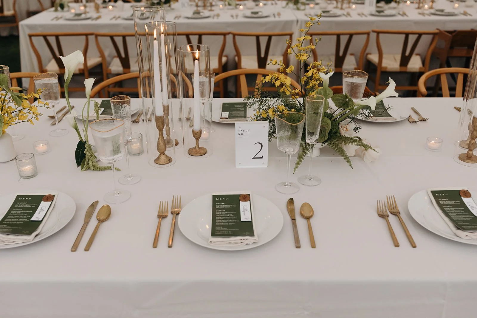 white wedding table with green and yellow florals and gold candles