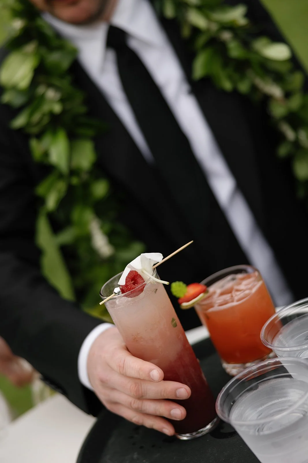 Oahu wedding planner Love Letter Weddings styled this red signature cocktail for a Paliku Gardens wedding, groom pictured grabbing his drink