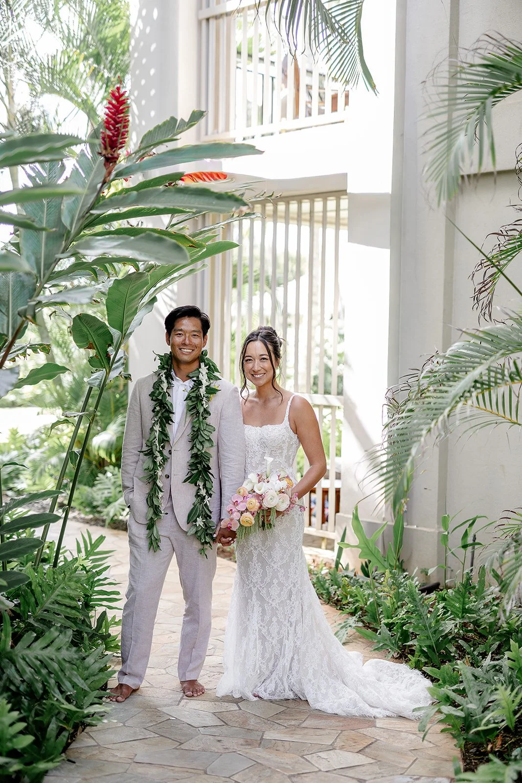 bride and groom next to tropical greenery