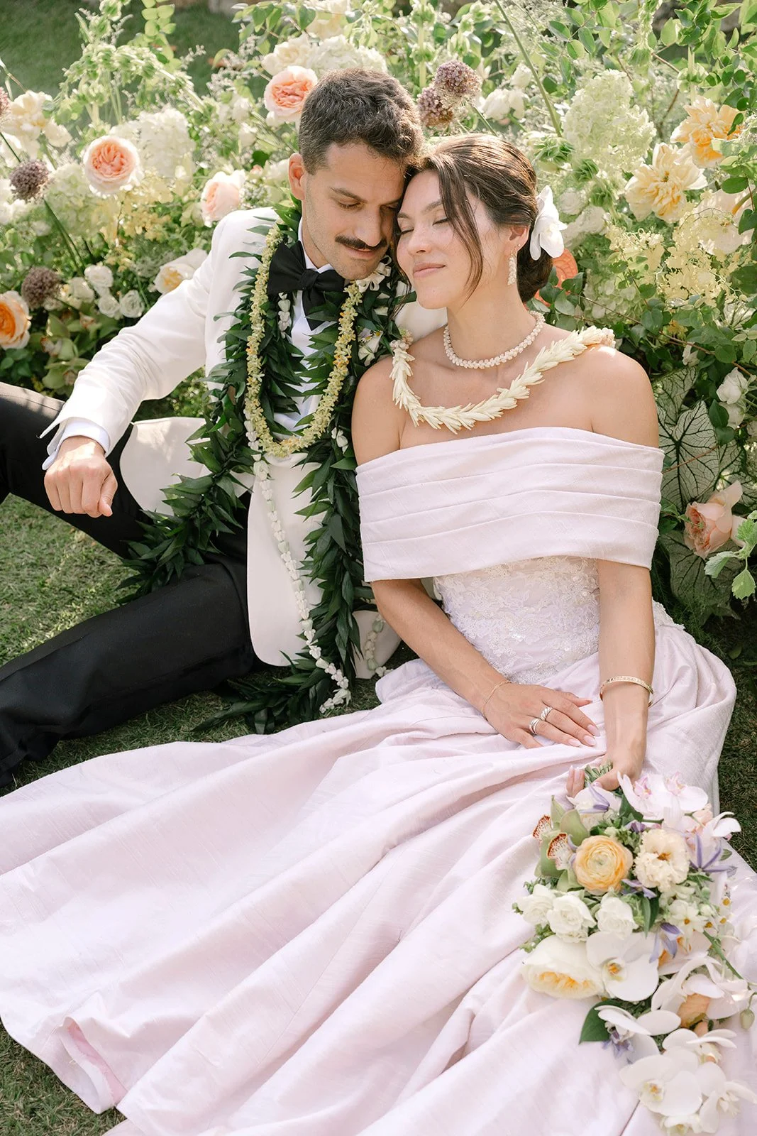 bride and groom sitting by pastel flowers