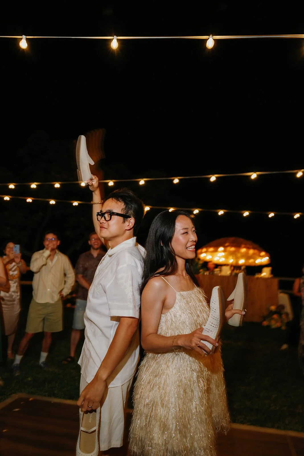 Bride and groom play his or hers game while holding their shoes