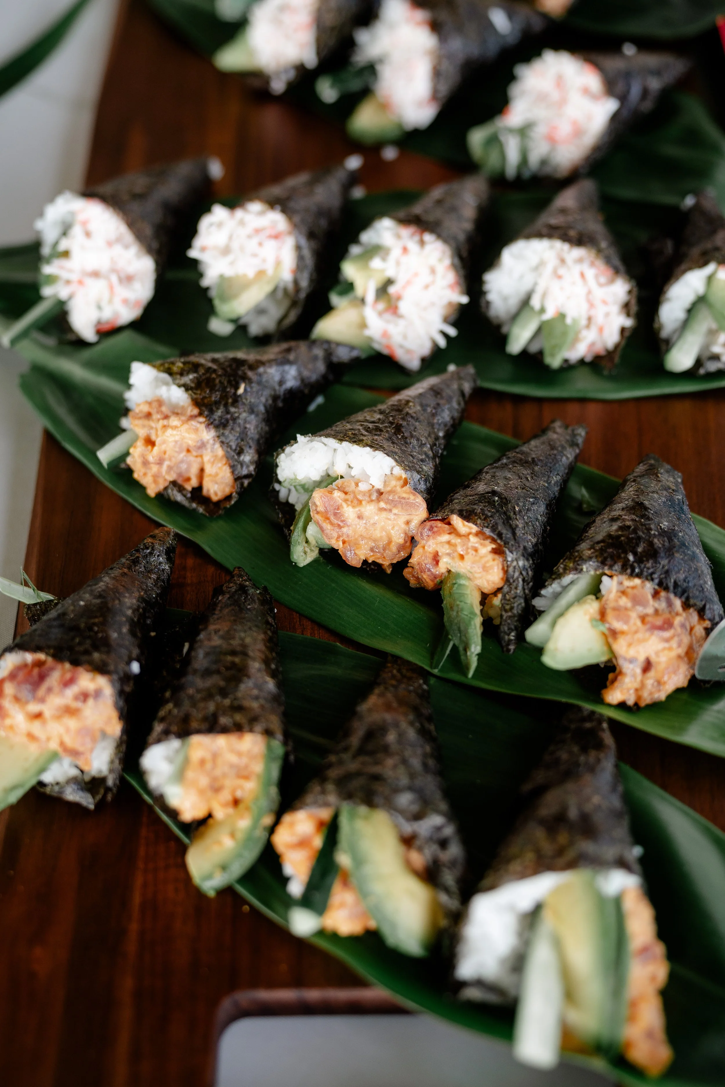 hand roll sushi displayed in a row on top of ti-leaf
