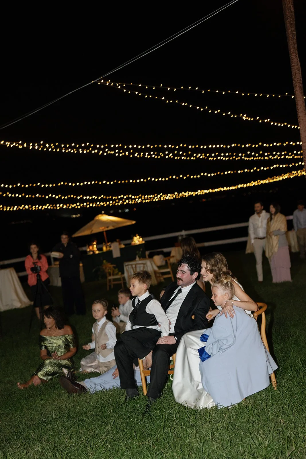 Bride, groom, and guests watch a fire knife performance together at their Paliku Gardens wedding, planned by Oahu wedding planner Love Letter Weddings