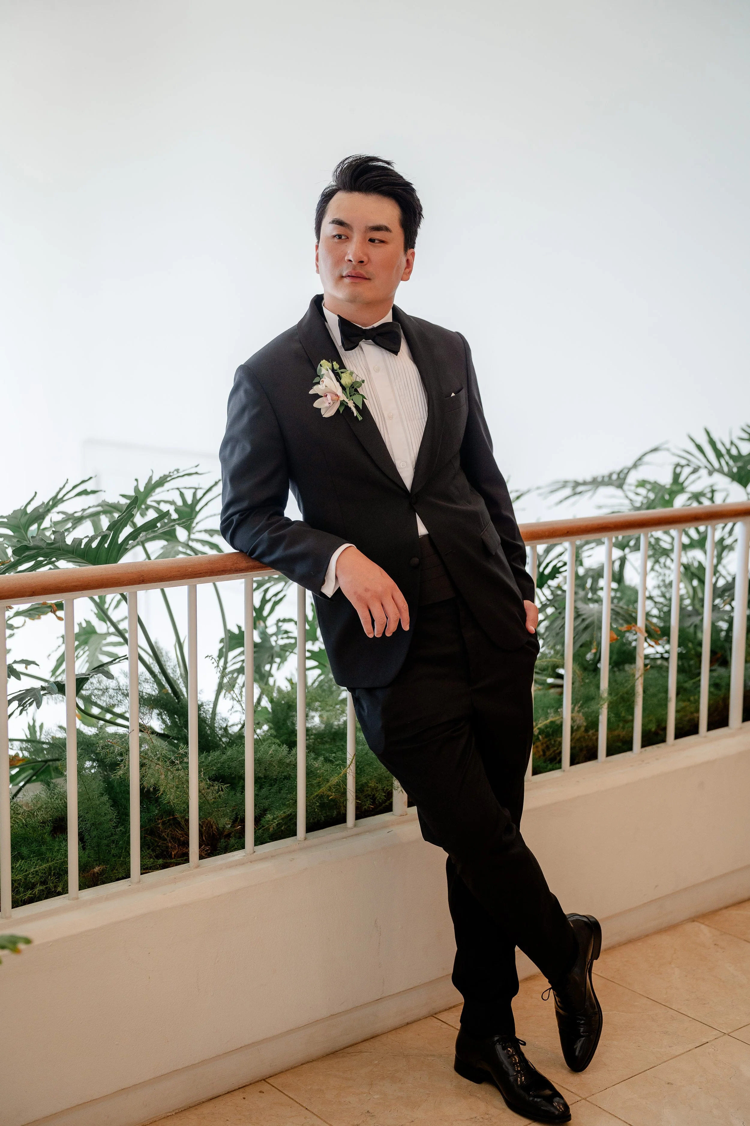 groom in suit and tie posing and leaning on balcony