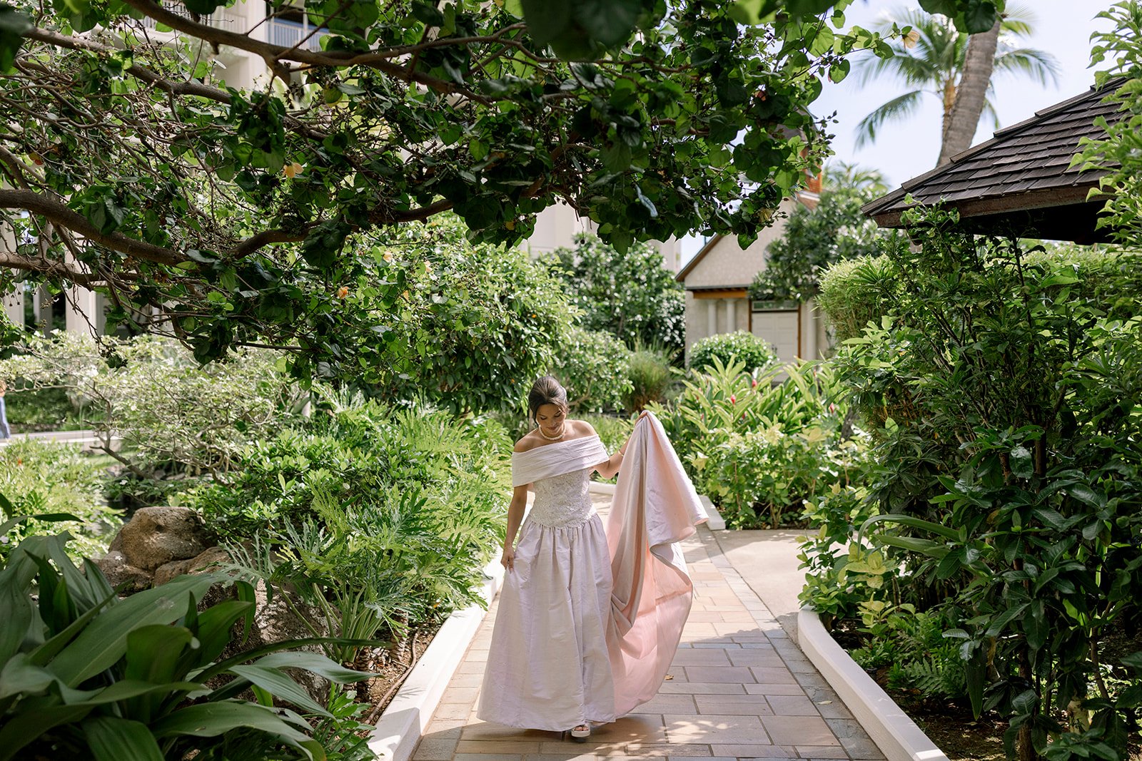 bride holding up dress next to trees