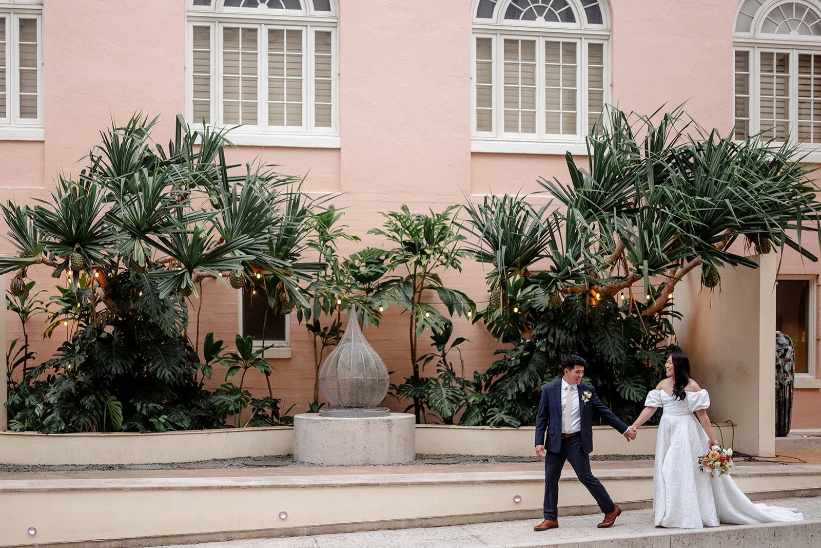 bride and groom walking through sculpture garden at capitol modern museum in hawaii
