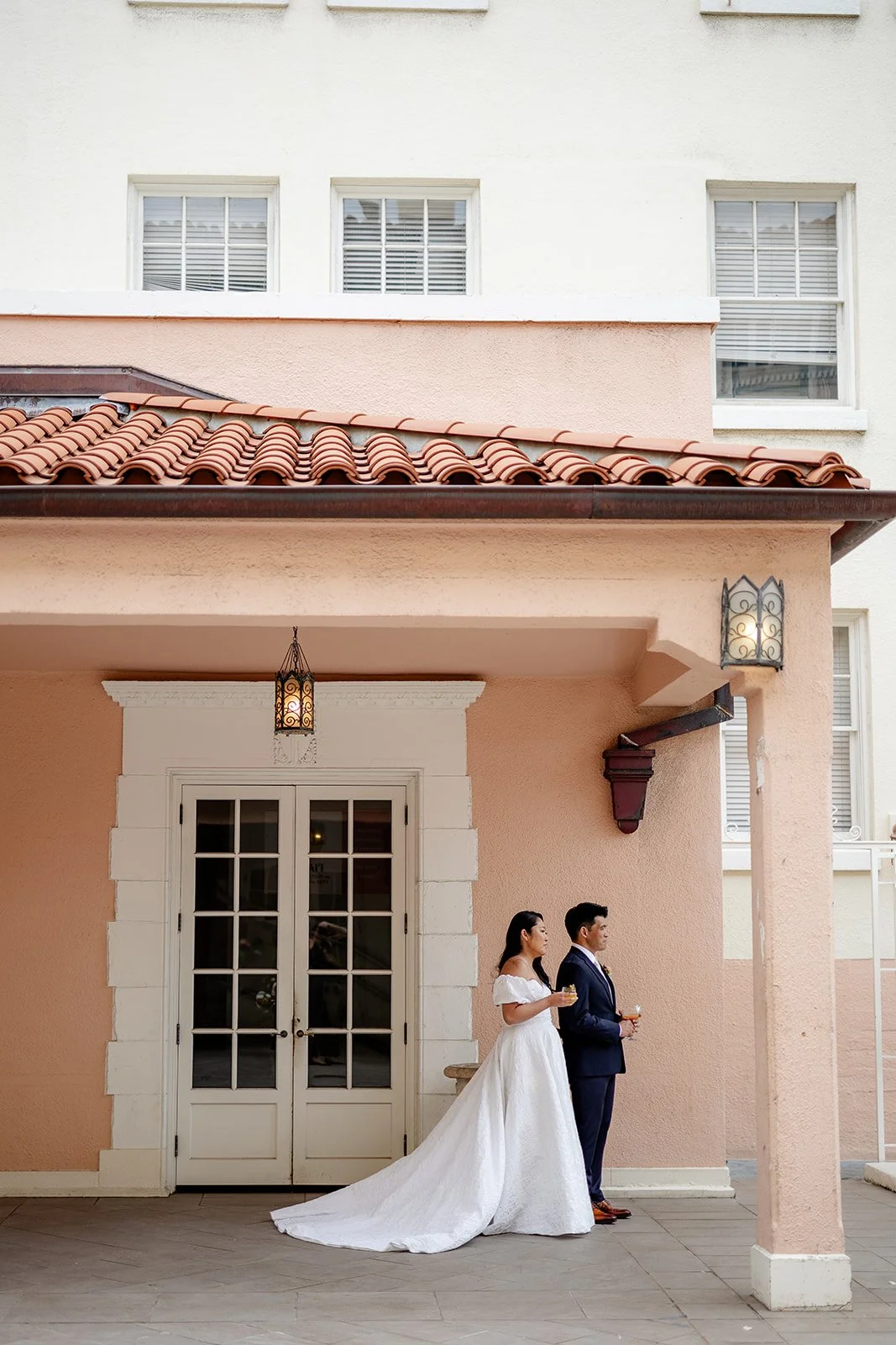 bride and groom by pink building