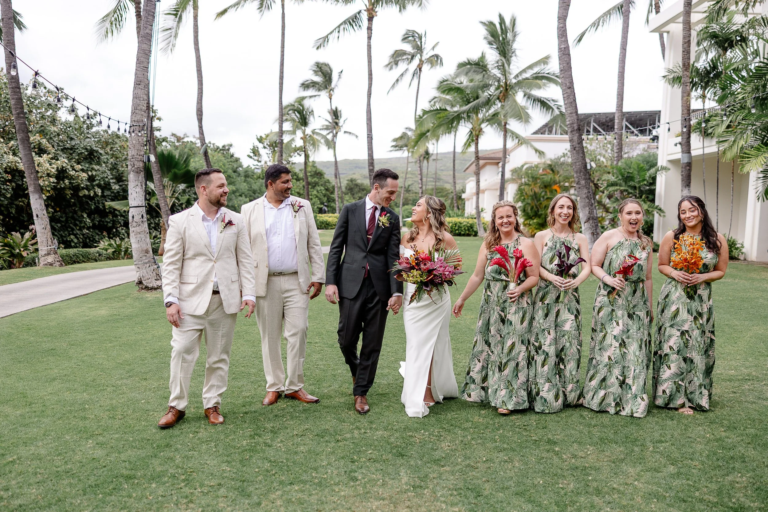 bride and groom walking with wedding party in tropical attire in Hawai'i