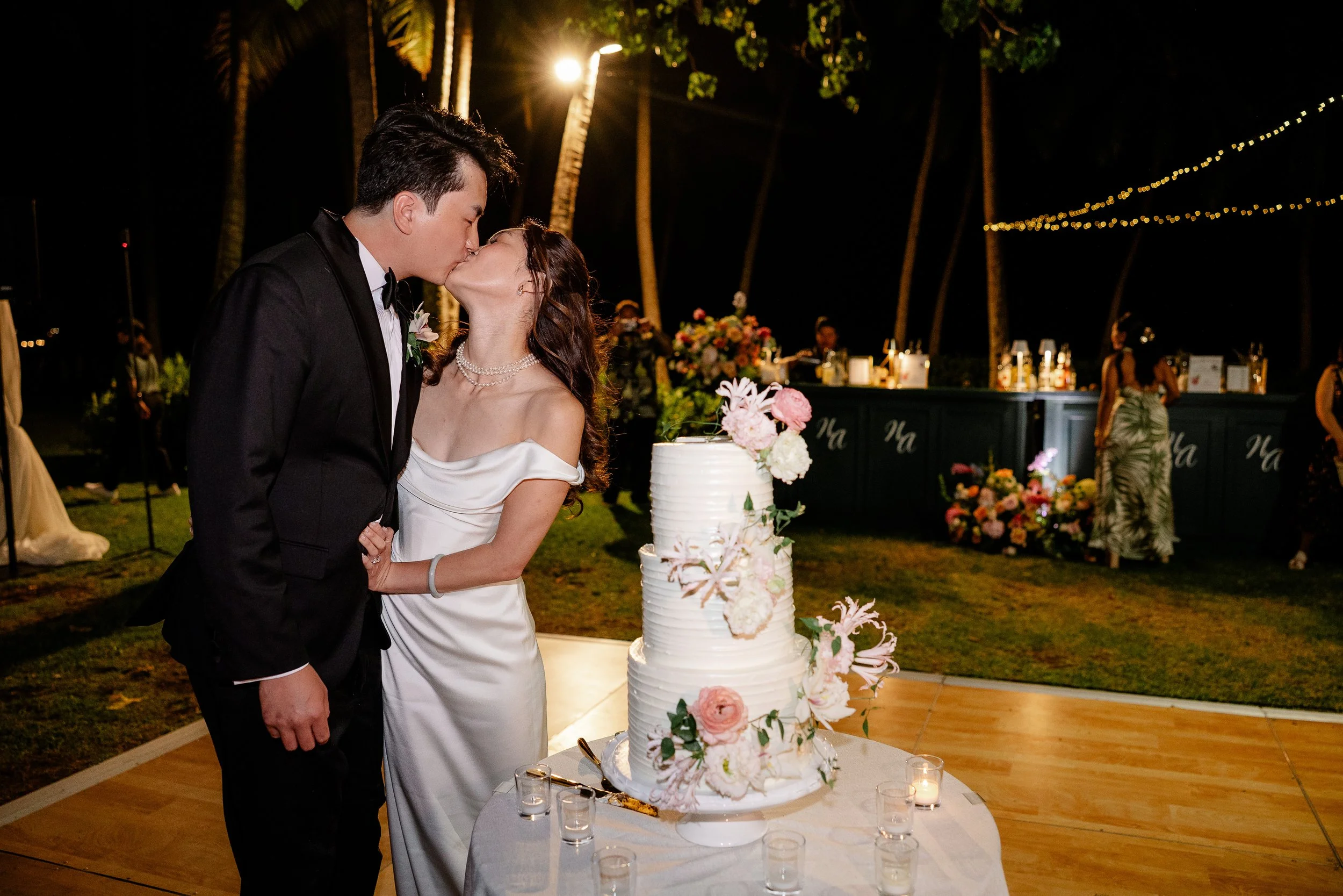 bride and groom kissing next to wedding cake
