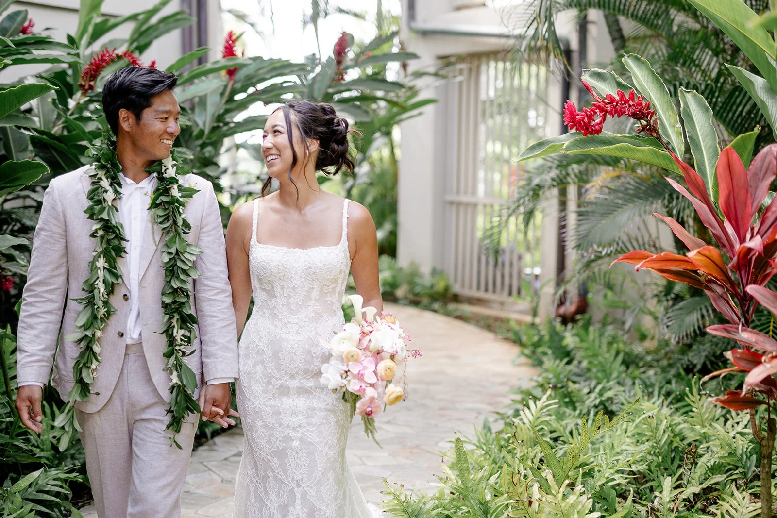 bride and groom walking through tropical greenery