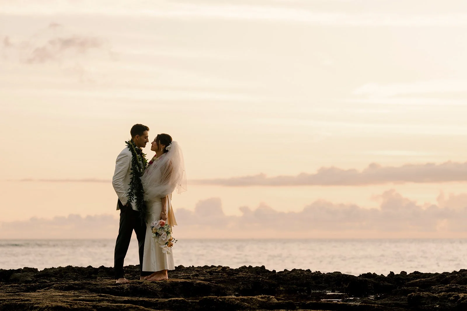 bride and groom looking at each in front of sunset in hawaii