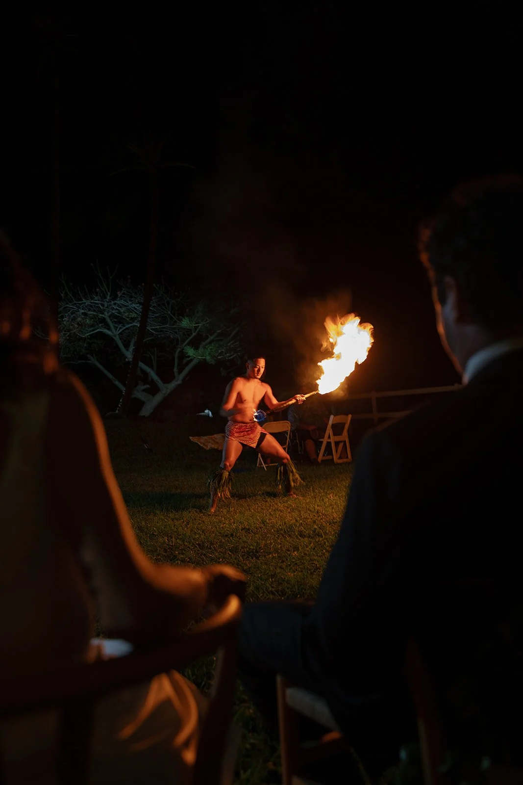 Bride and groom watch a fire knife performance at their Paliku Gardens wedding, planned by Hawaii wedding planner Love Letter Weddings