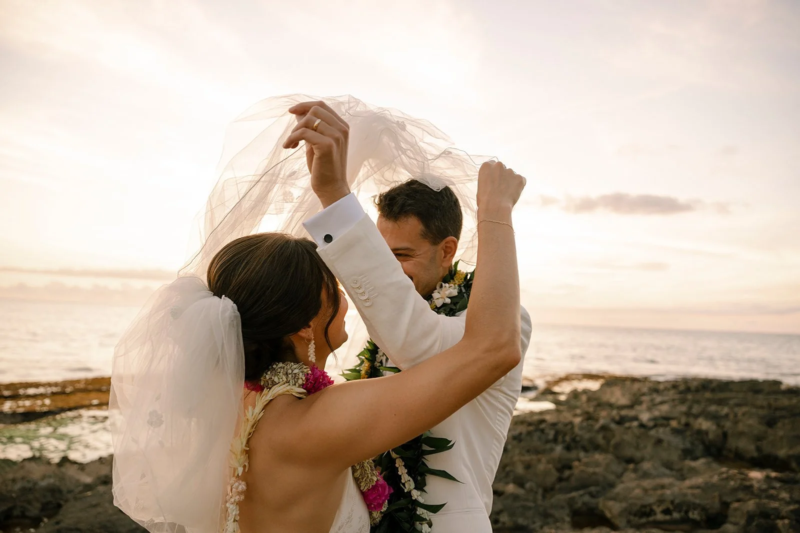 bride and groom with veil in front of sunset in hawaii