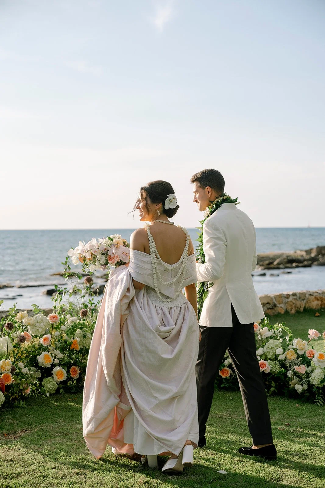 bride and groom near pastel flower arrangement by the ocean