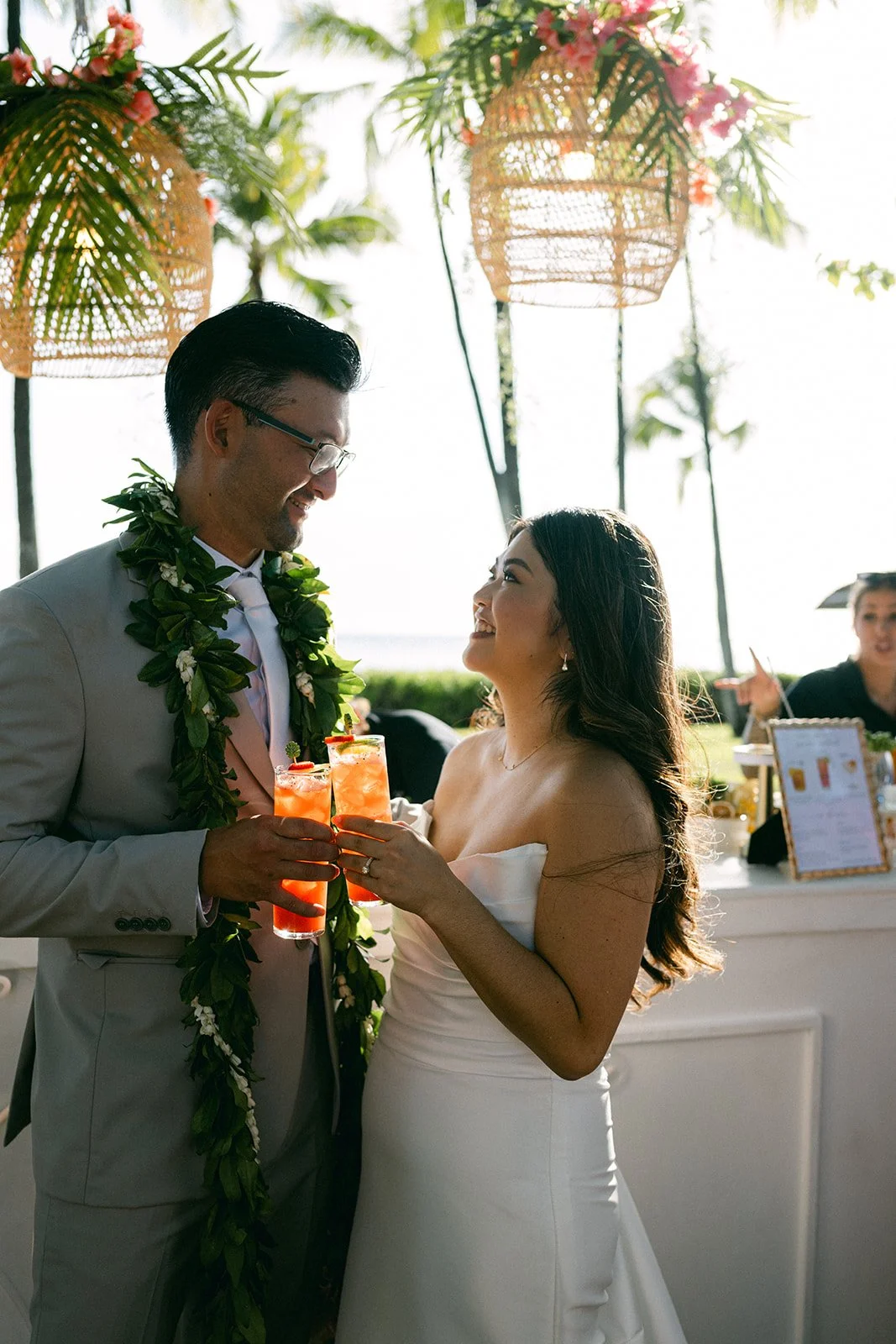 bride and groom holding drinks under rattan lanterns