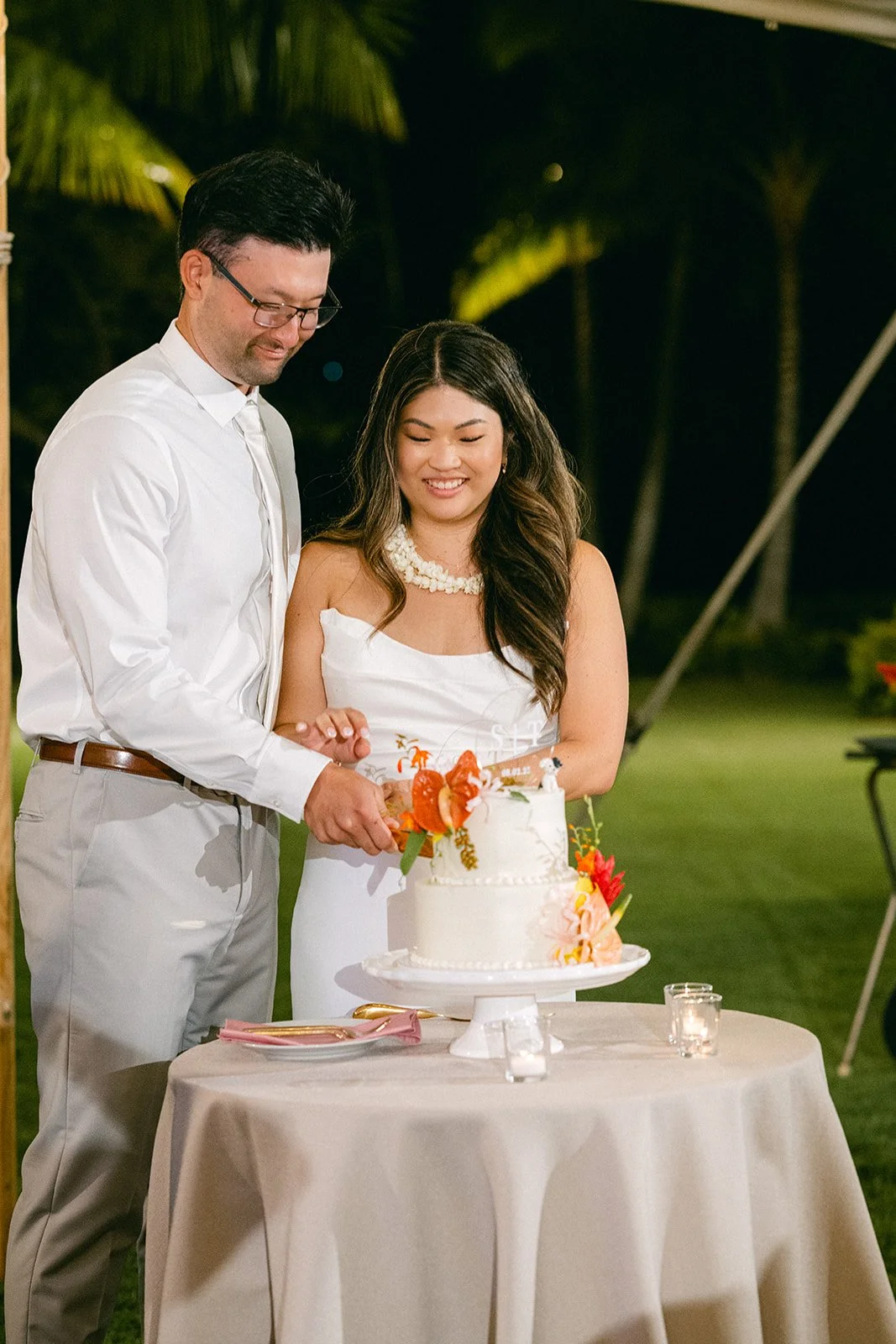 bride and groom cutting cake with tropical flowers