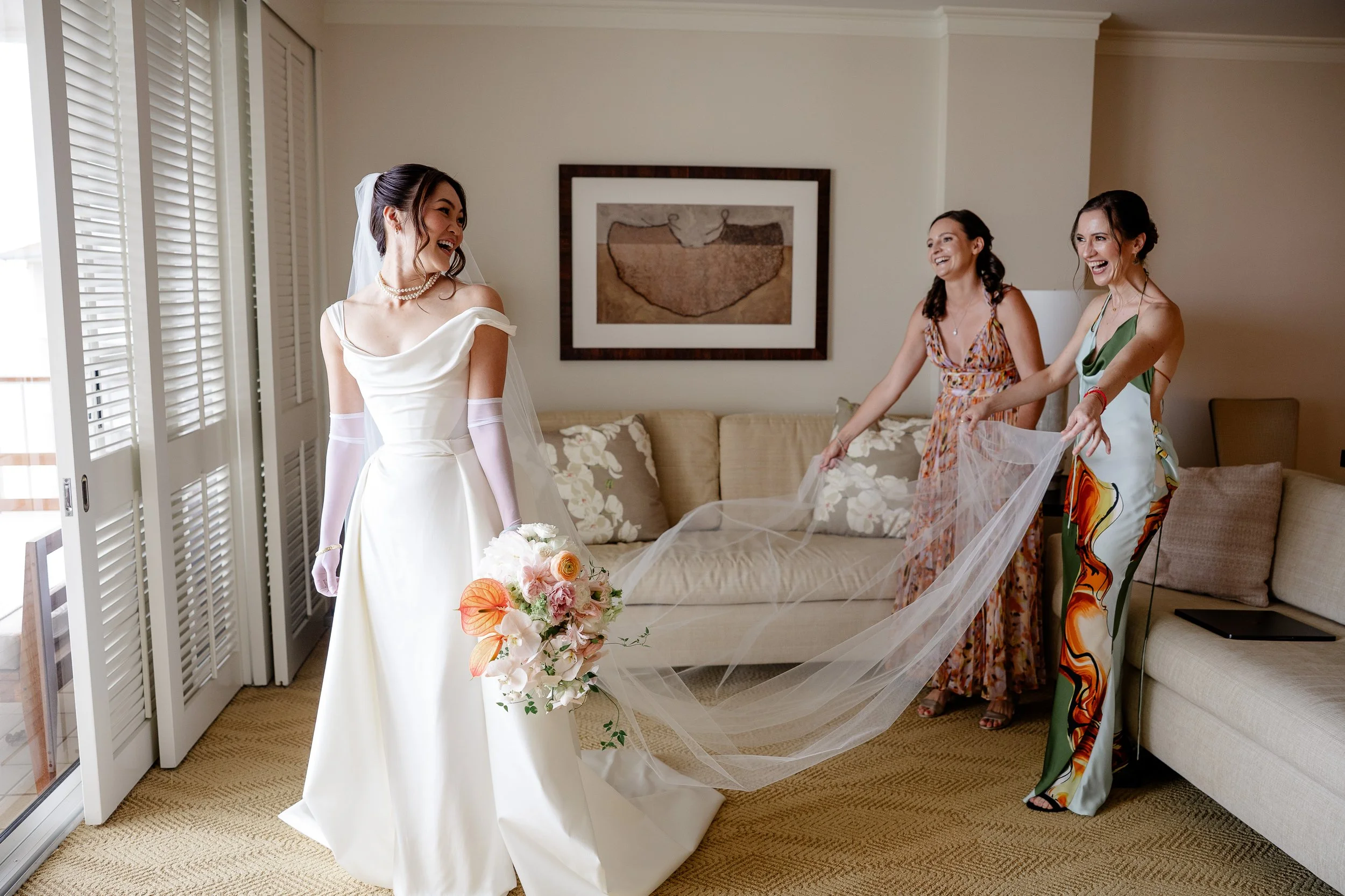 bride in wedding dress with bridesmaids fixing veil