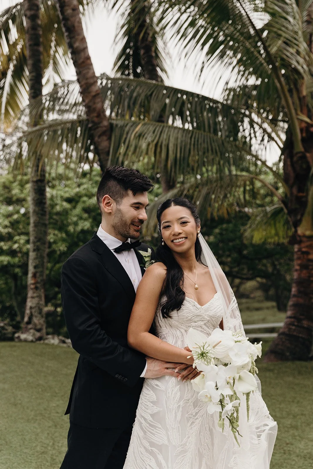 bride and groom in front of palm trees in hawaii
