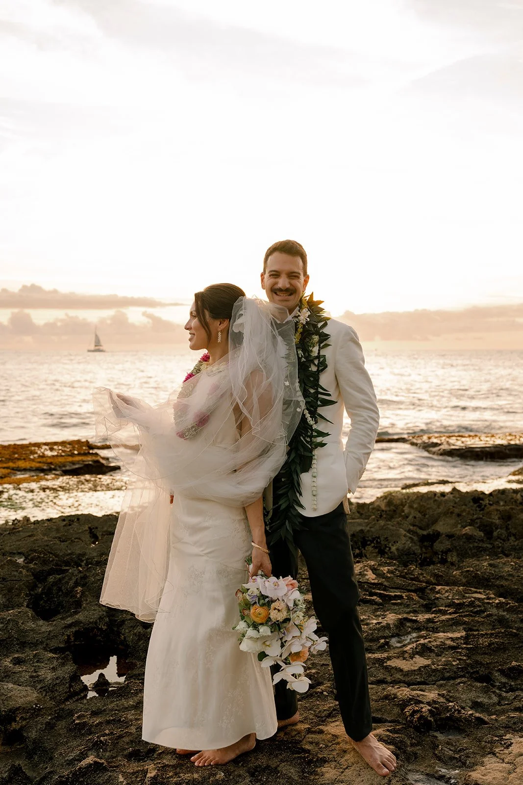 bride and groom in front of sunset in hawaii