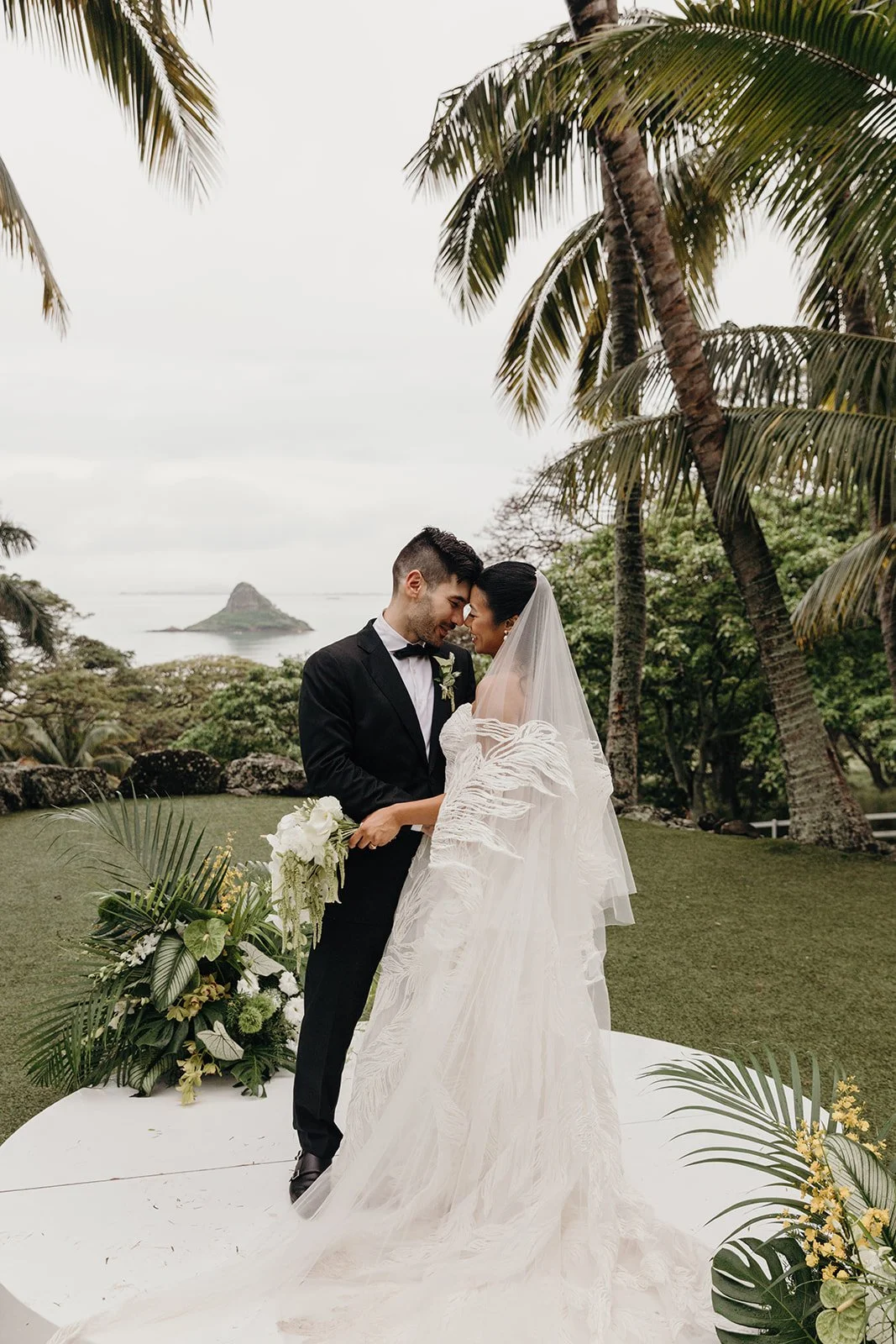 bride and groom in front of palm trees in hawaii