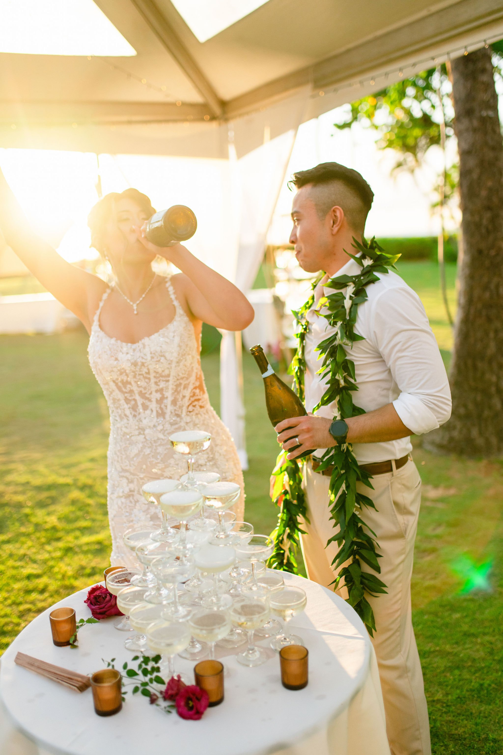 bride drinking champagne while pouring champagne tower