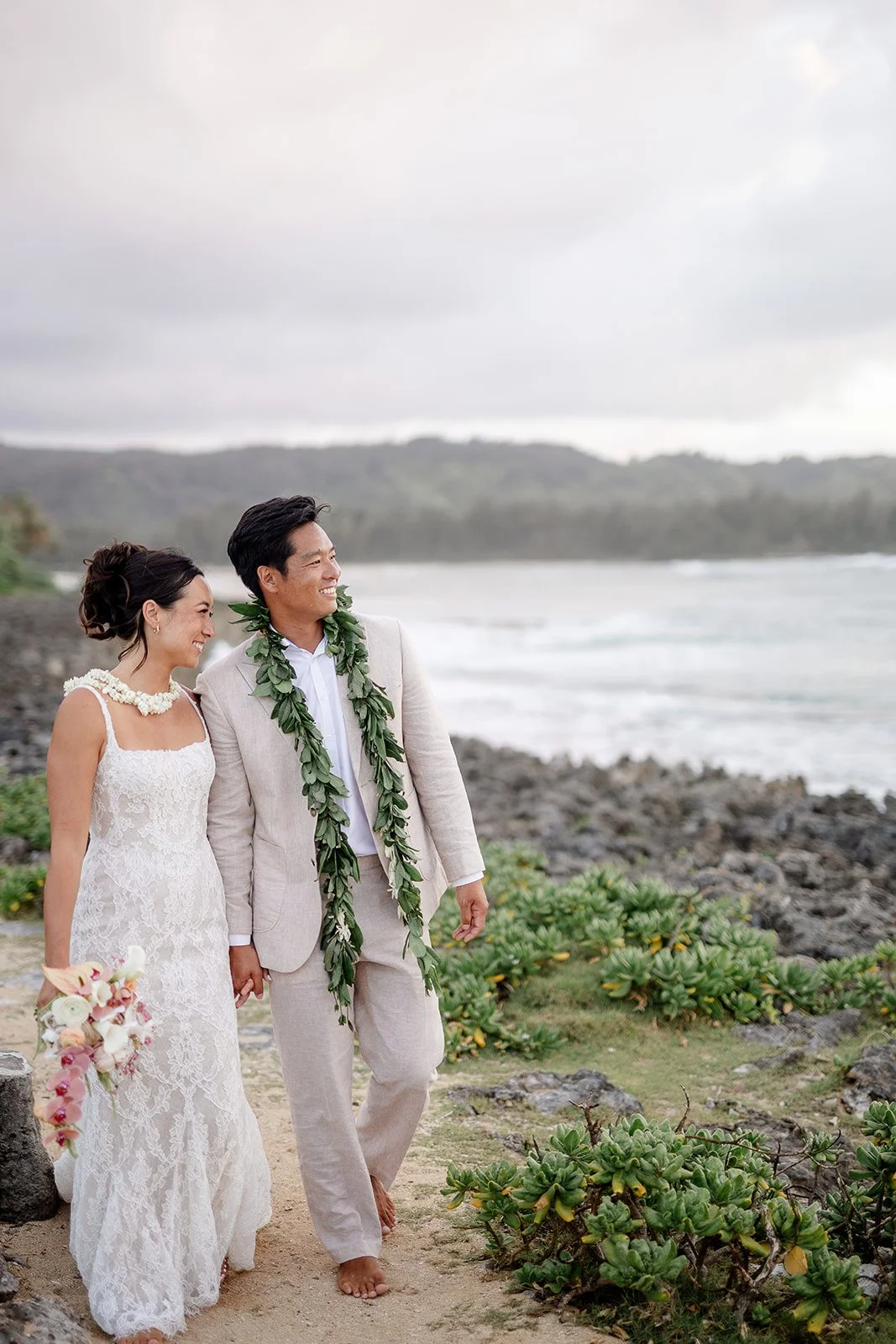 bride and groom walking along the shore in hawaii