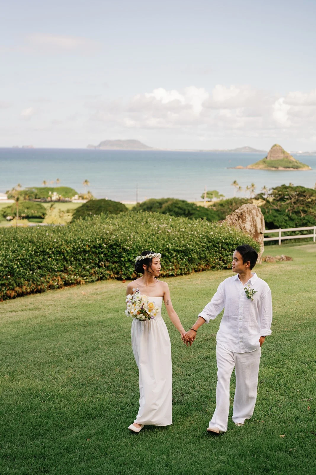 Bride and groom holding hands and walking together with beautiful Hawaii background