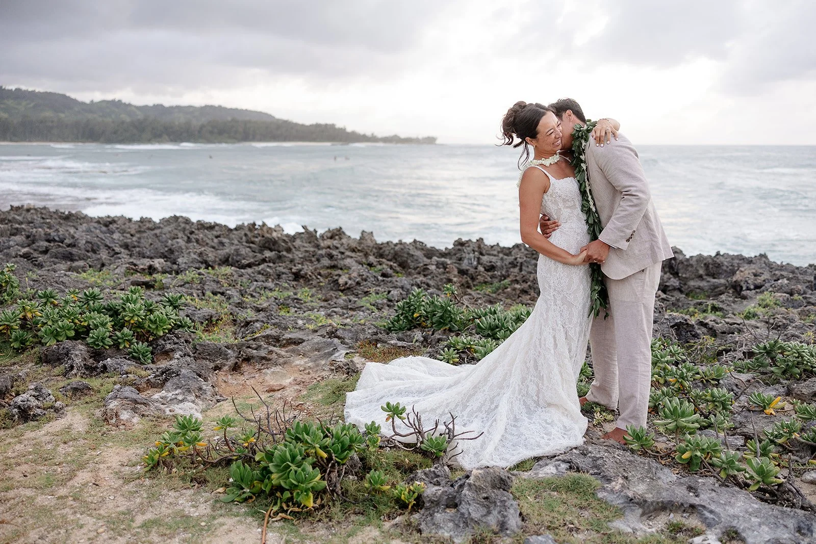 bride and groom kissing on the shore in hawaii