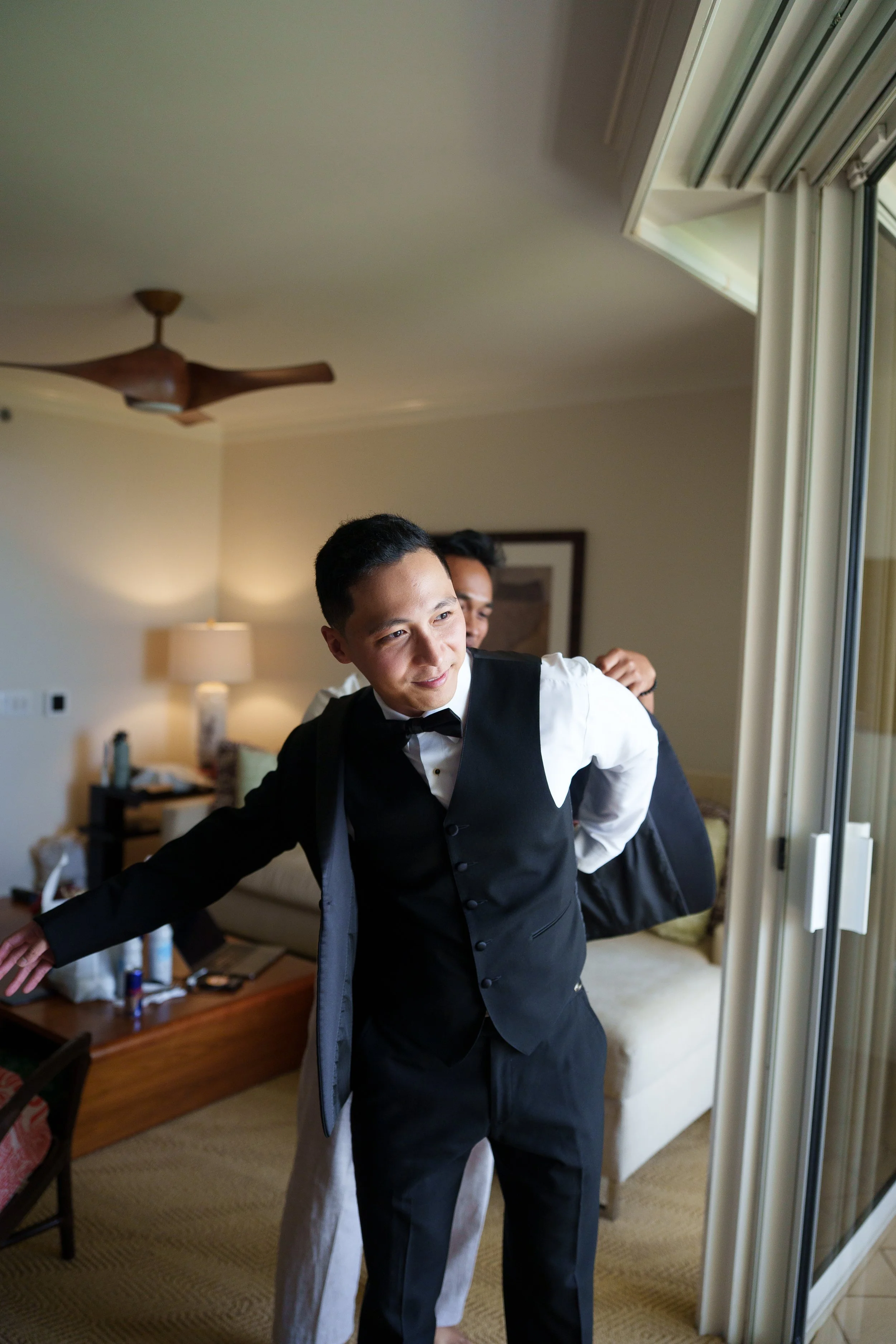 Family member helps groom put on jacket for a getting ready photo
