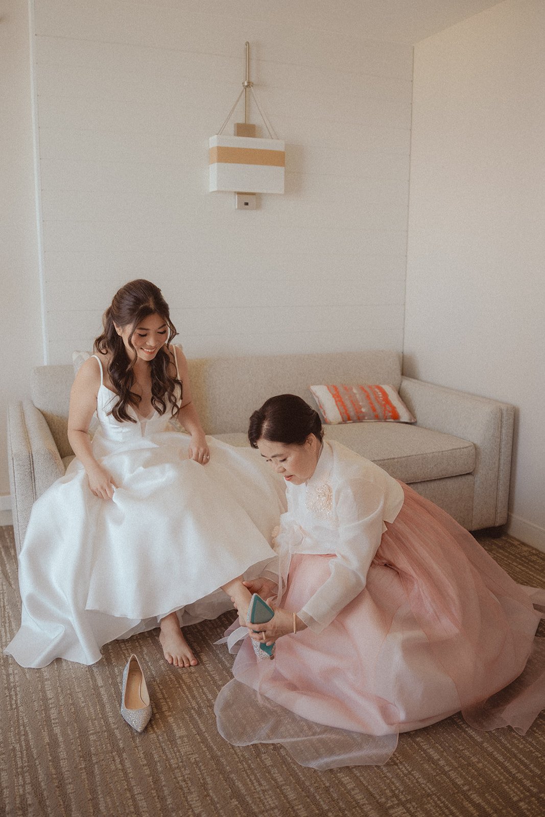 mother of bride helping bride put on shoes