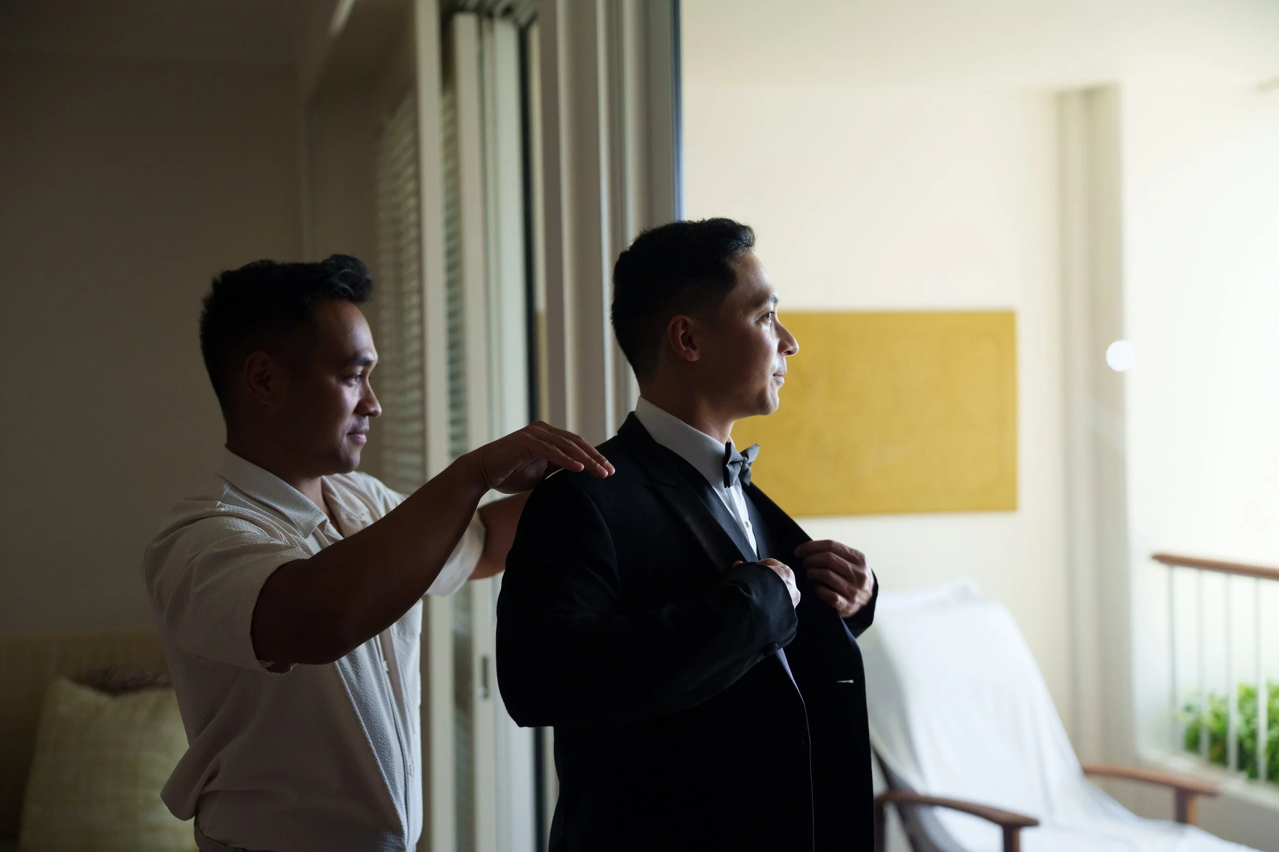 Family member helps groom fix jacket for a getting ready photo