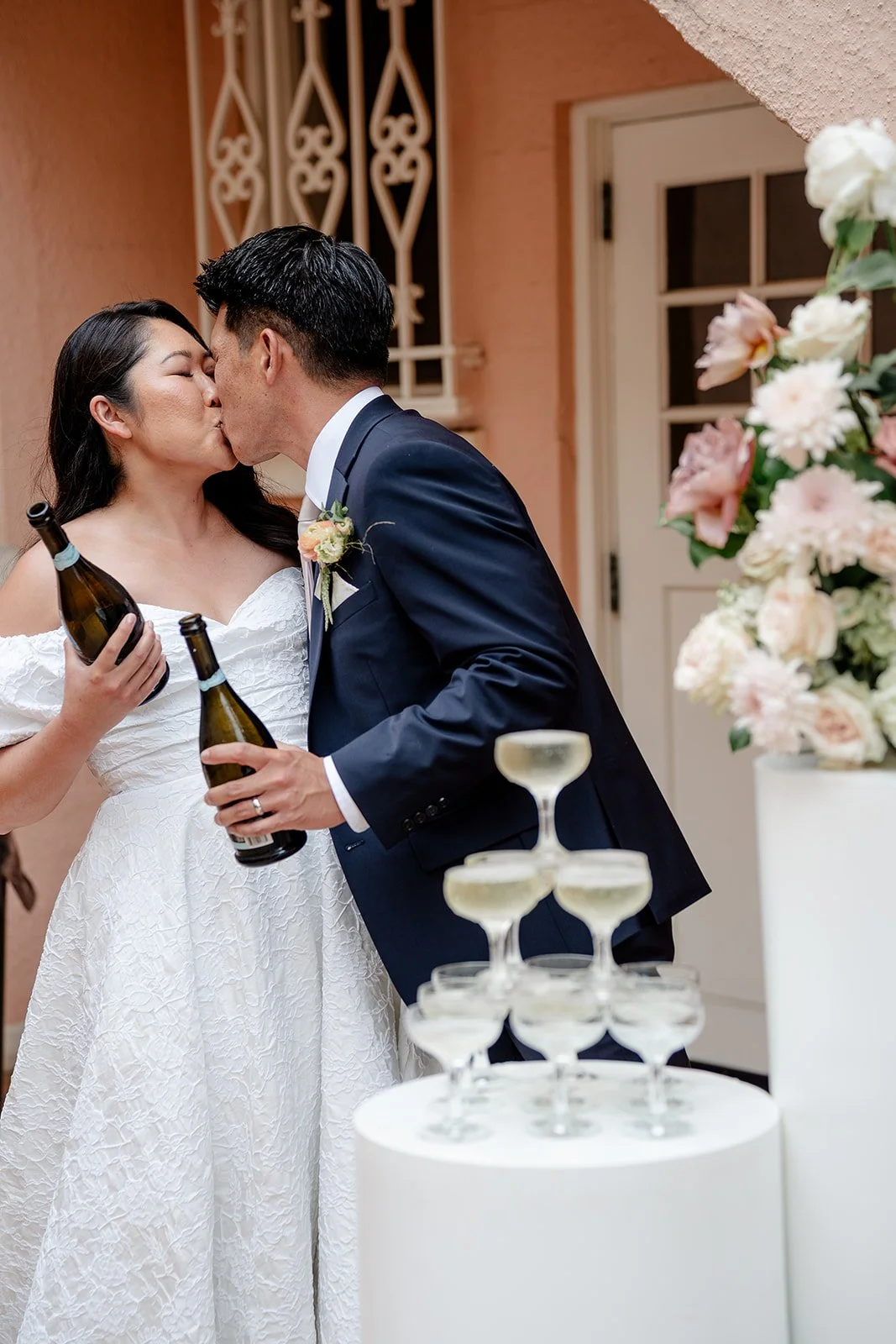 bride and groom kissing after pouring champagne tower