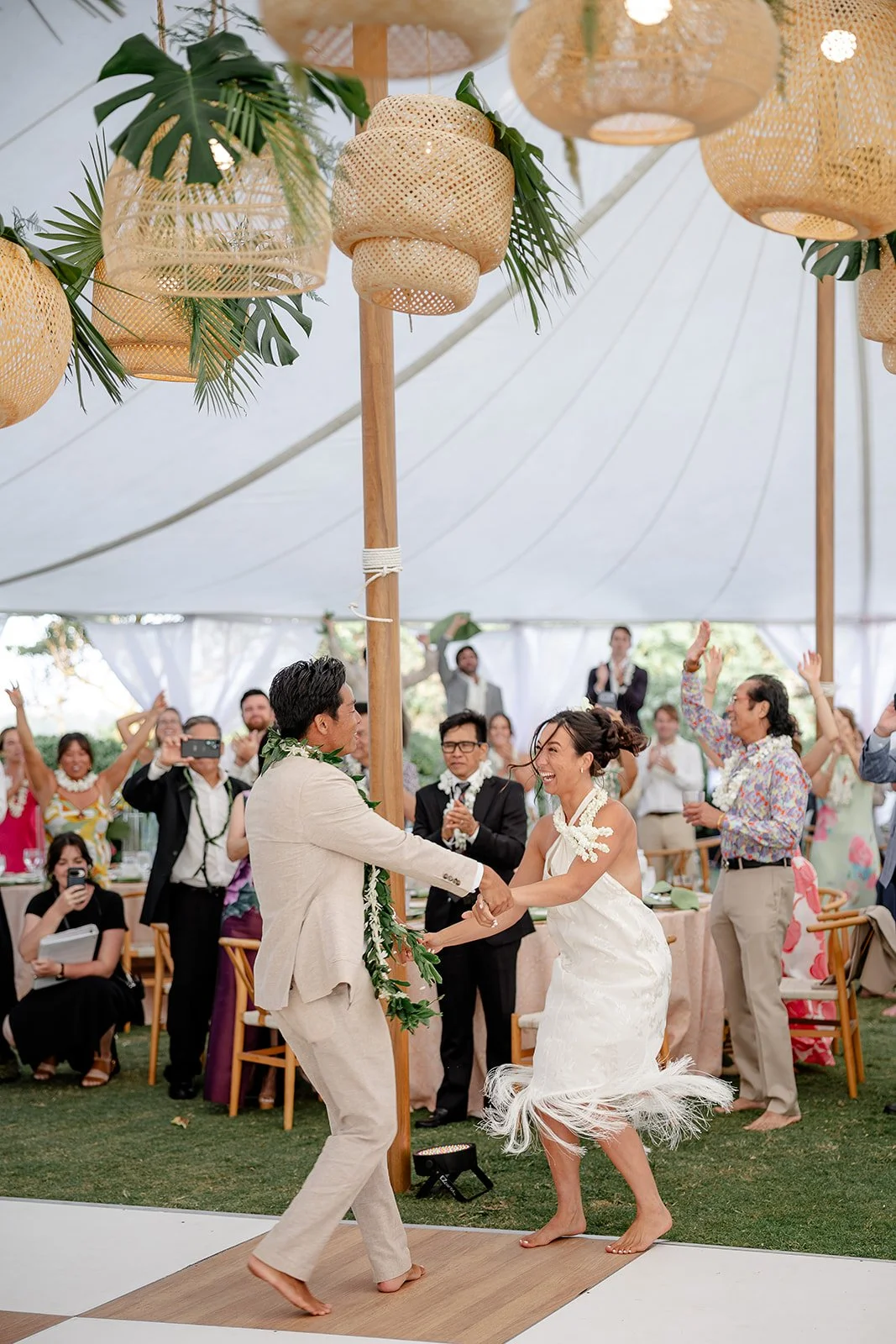 bride and groom dancing under rattan lanterns with greenery