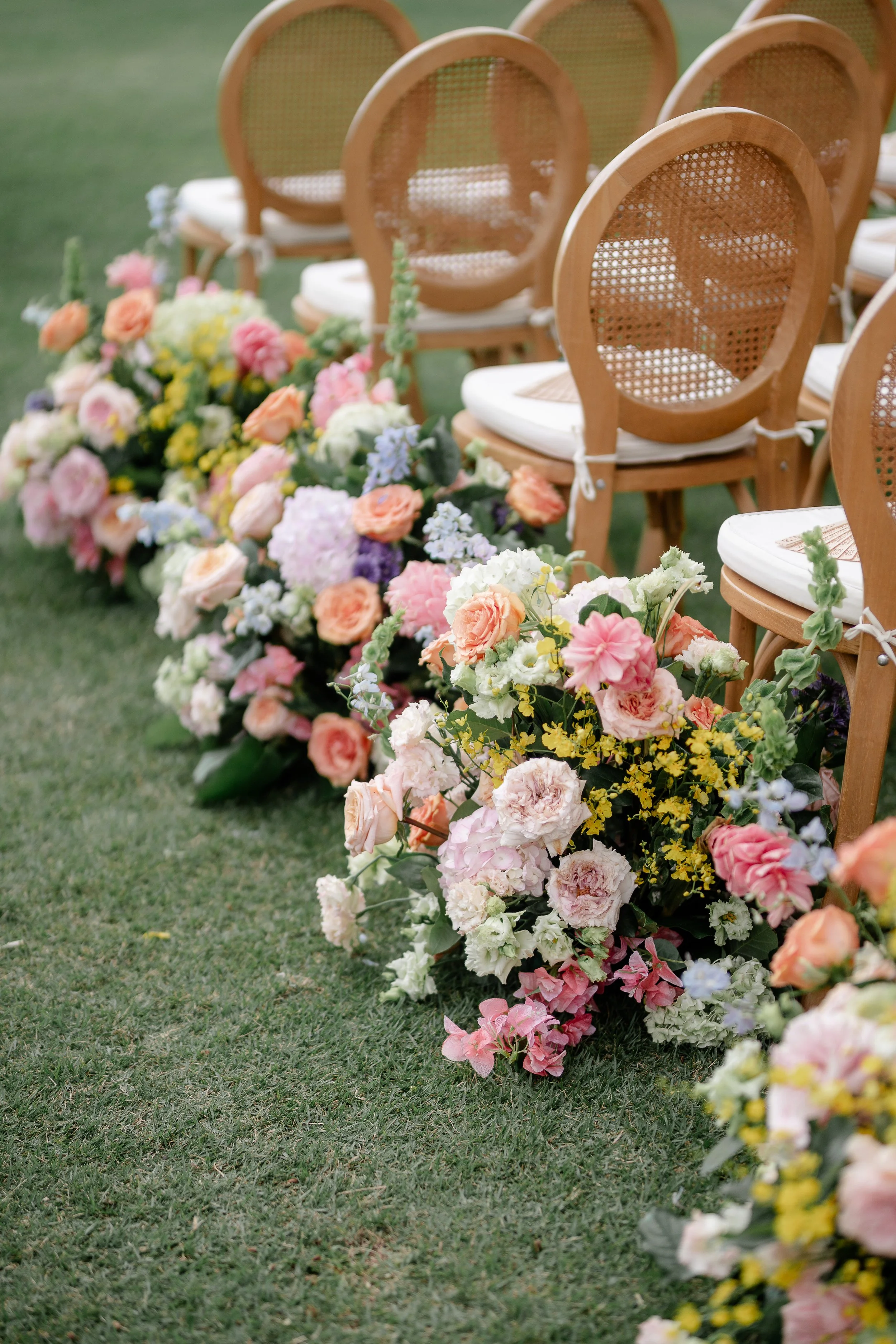 colorful wedding florals next to ceremony chairs